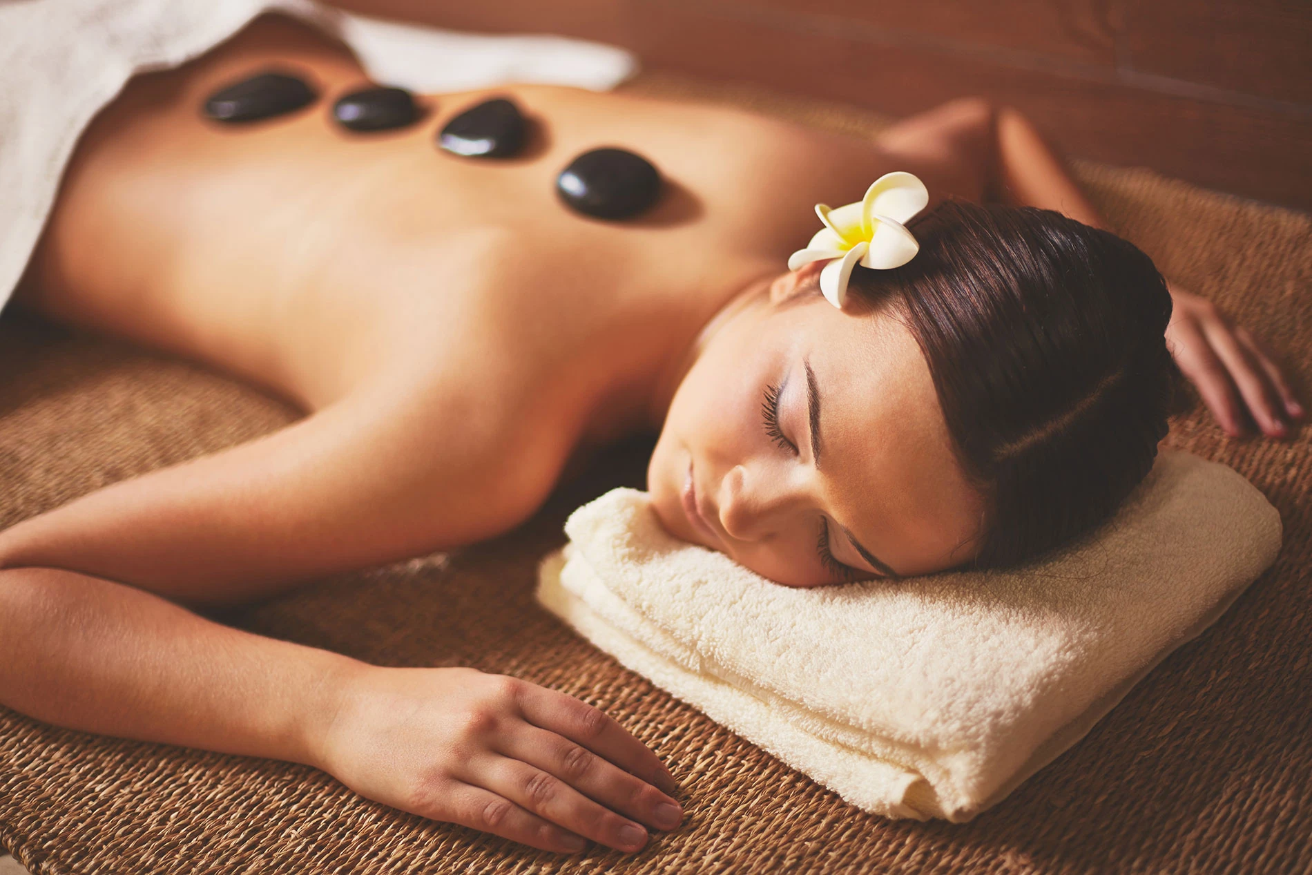 woman laying on a towel with stones on her back